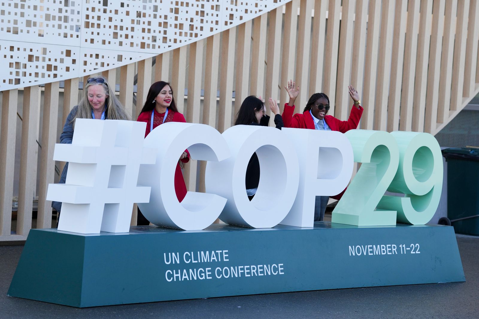 An image of people standing behind 'COP29' logo stand.