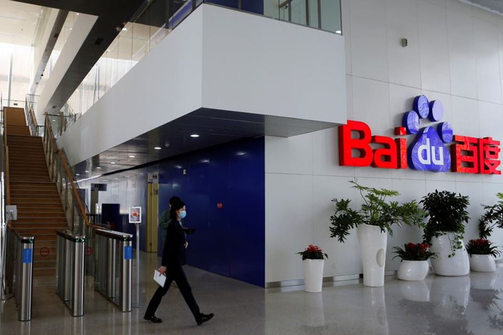 FILE PHOTO: People walk near a Baidu logo at the company headquarters in Beijing, China April 23, 2021. REUTERS/Florence Lo/File Photo
